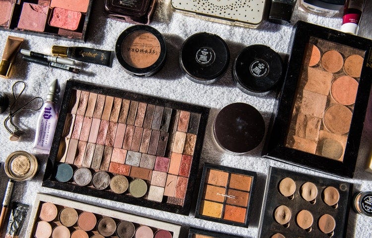 A photograph of various containers and types of makeup artfully arranged on a table.