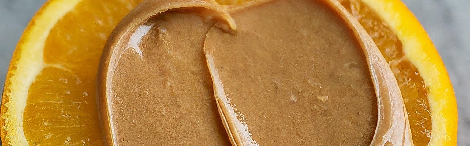 Creamy peanut butter on an orange slice