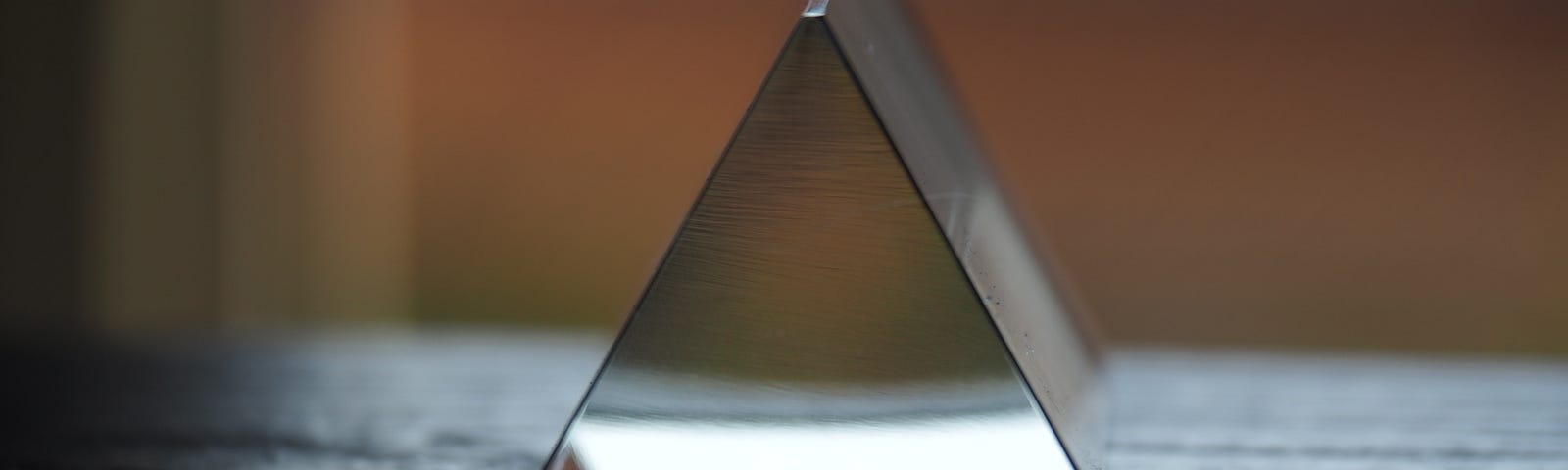 A metallic cut-out triangle laying on a window sill — like the embodiment of ‘3’.