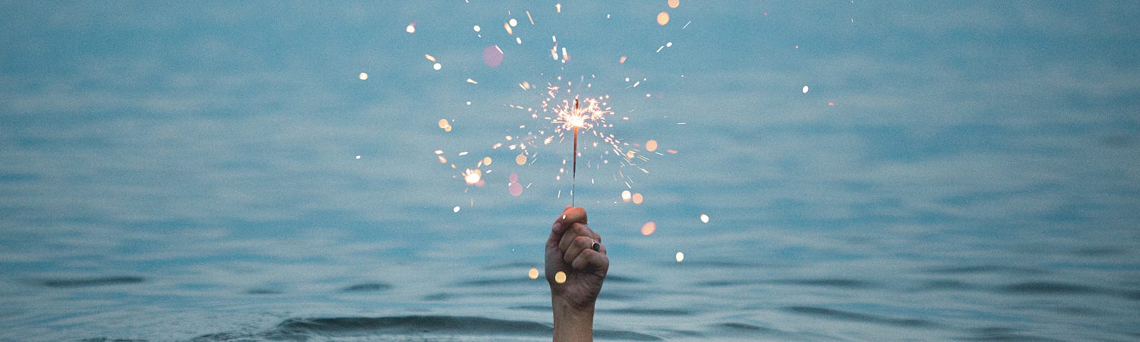 Craving love. Self-development. A person underwater holding a sparkler above the water.