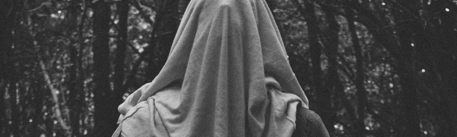 A cloaked man standing with a sheet over his face; A visual representation of suppressed rage.