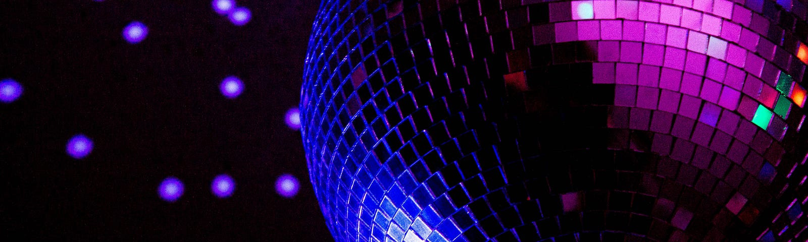 A disco glitter ball reflecting indigo and violet lights