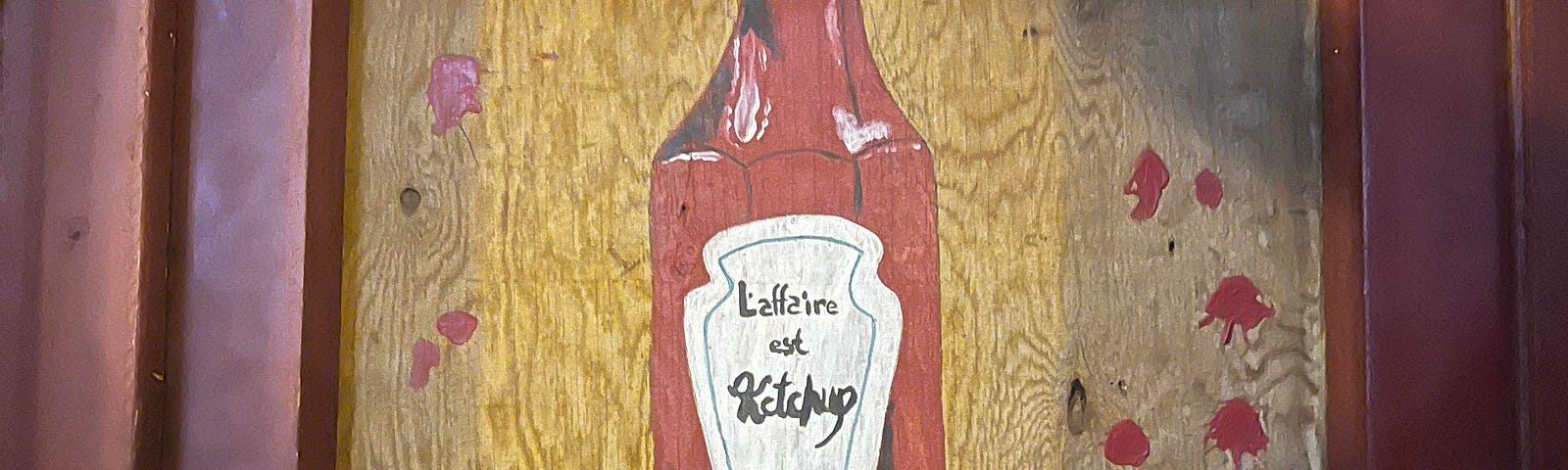 The front door to the restaurant, with an old fashioned ketchup bottle painted on plywood.