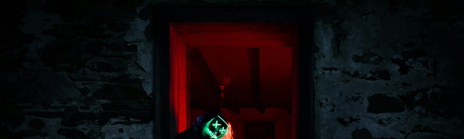 A green-masked man blocks the entrance of a red-lit room in a dramatic dark grey atmosphere.
