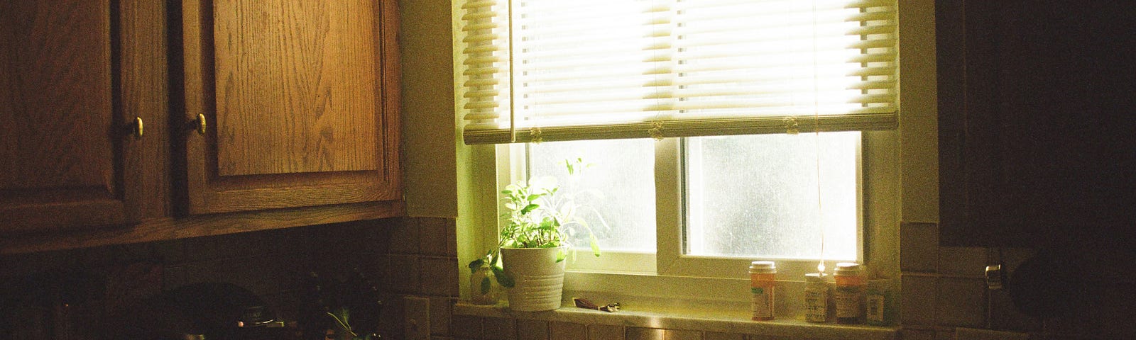 dirty dishes on a kitchen counter. light comes through the window over the sink