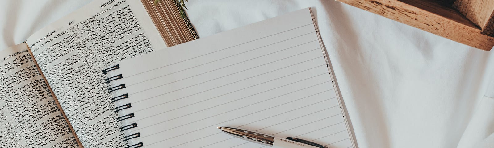 A notebook and a pen on a comfortable bed. Shows the setup of a prolific writer.