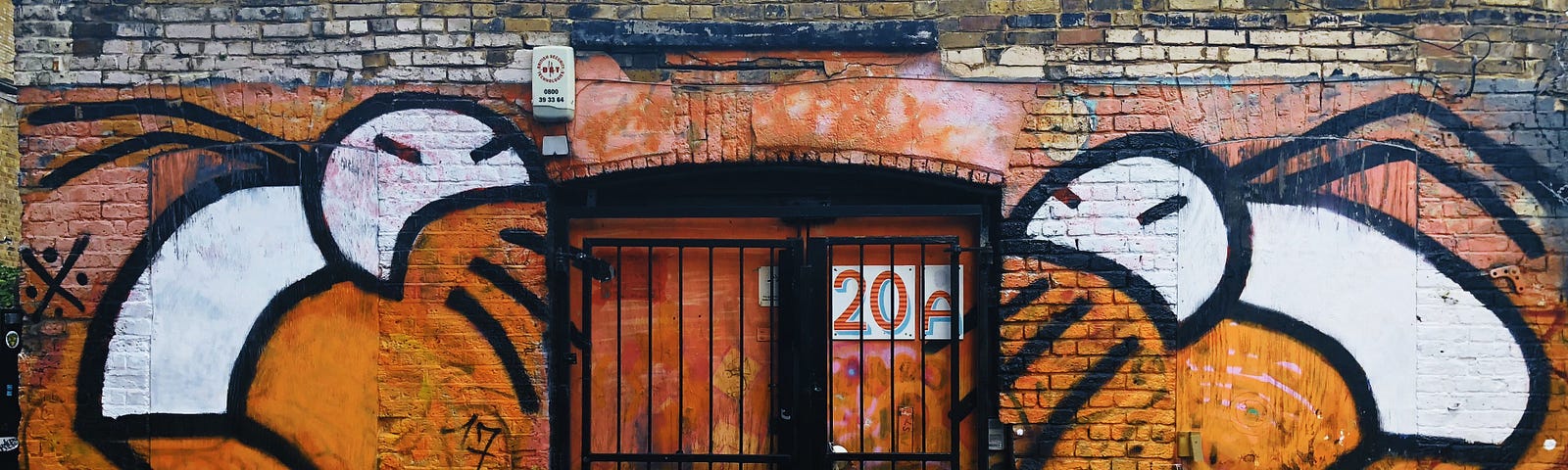 iron gate on brick wall covered in graffiti art