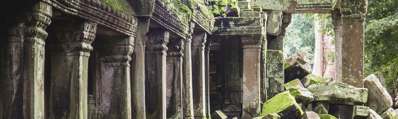 A photo of ancient ruins being enveloped by foliage and time