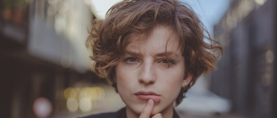 Portrait Photo of Woman Posing with Her Thumb Below Her Lip