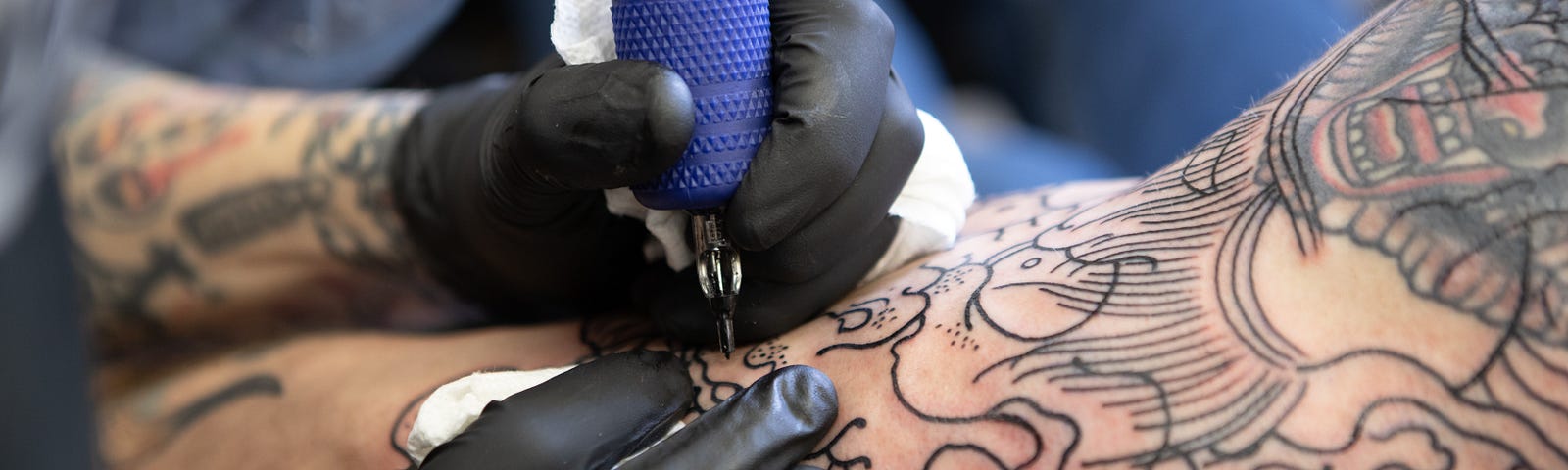A close up shot of someone having a tattoo on their arm