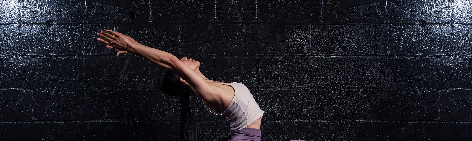 woman in front of a black wall doing yoga