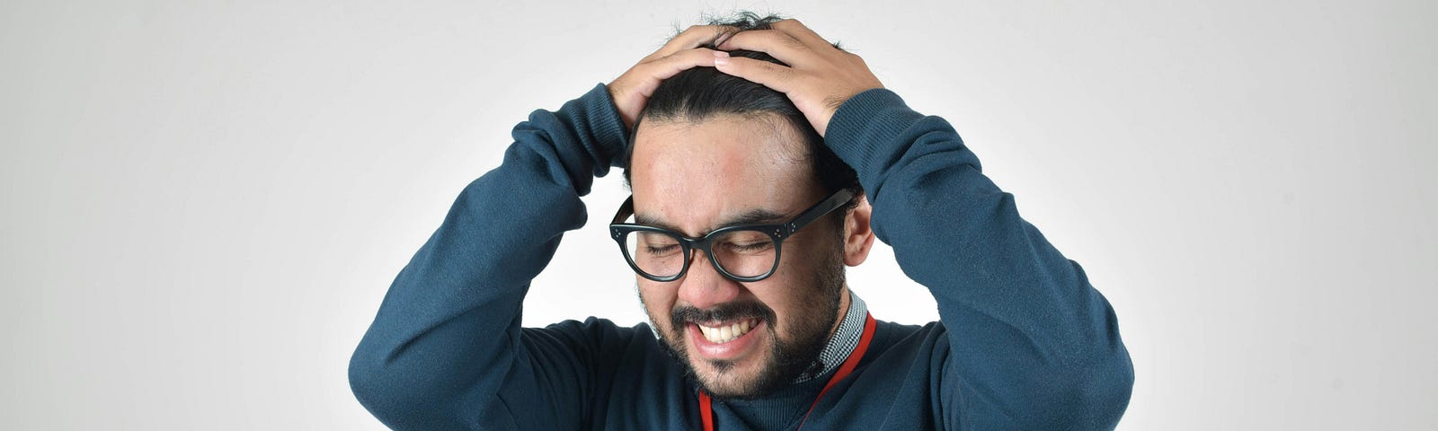Stressed and anxious man with glasses holding his head