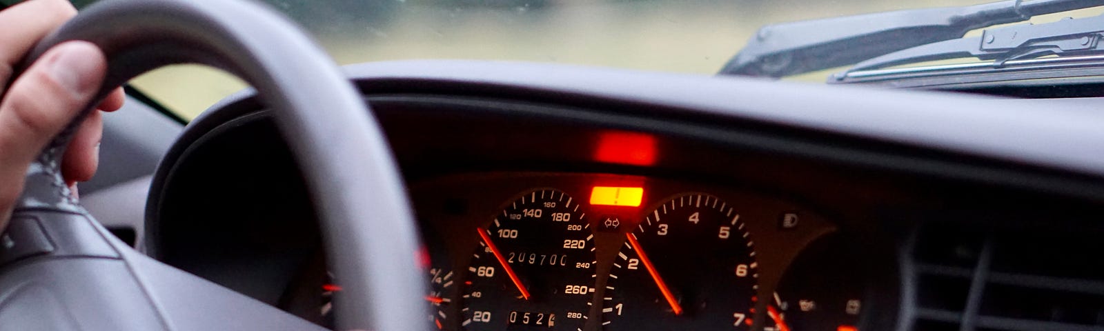 Car dashboard and steering wheel with hands on it