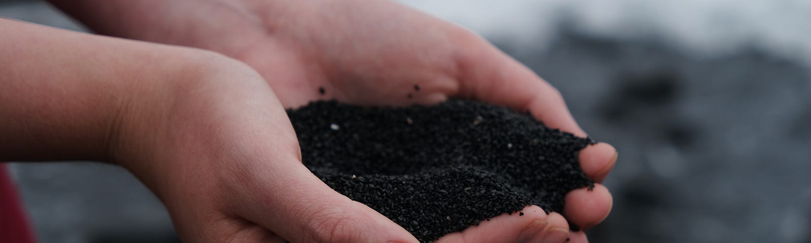 Two hands holding a small pile of dark soil.