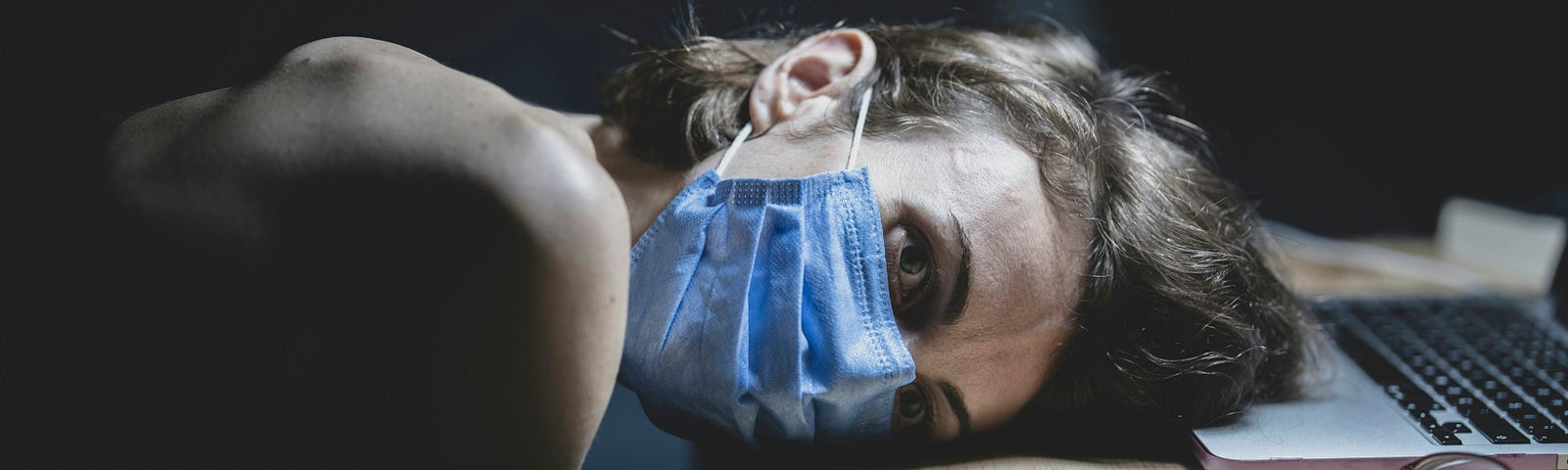 exhausted woman with head on desk at laptop