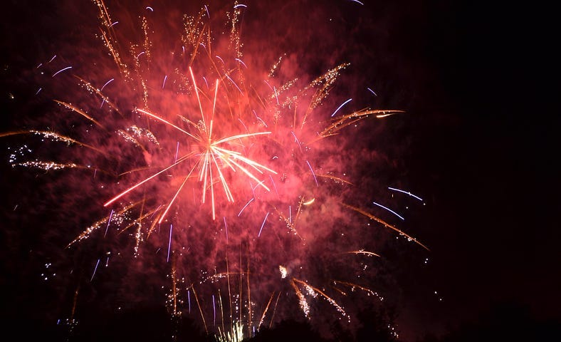 A pink fireworks display with white stars.