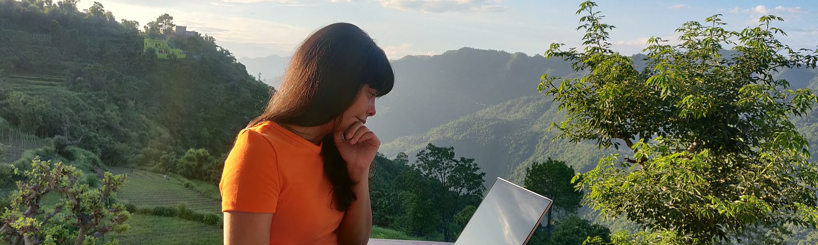 A woman looking into a laptop near a mountain