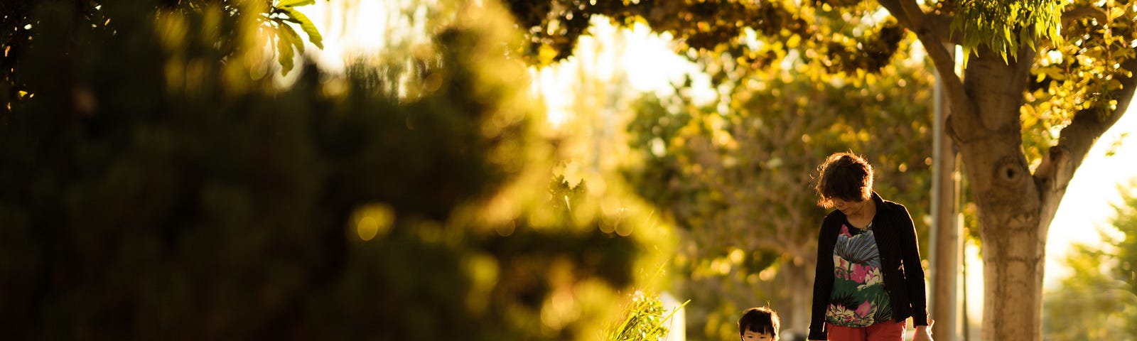 Woman and child walking on tree lined footpath