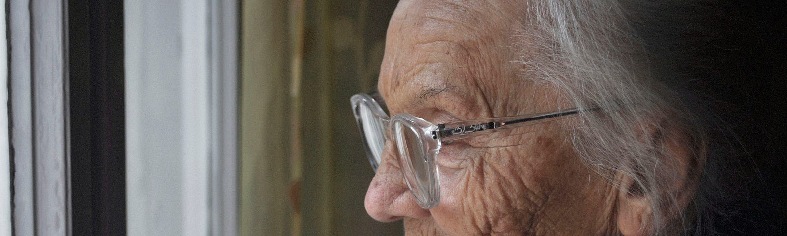 A close-up of an old lady with gray hair and wearing glasses.