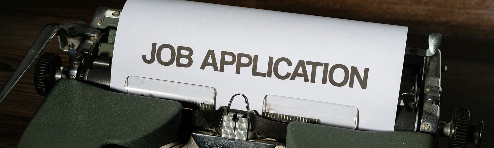 Typewriter with a paper in it, showing the words “Job Application”