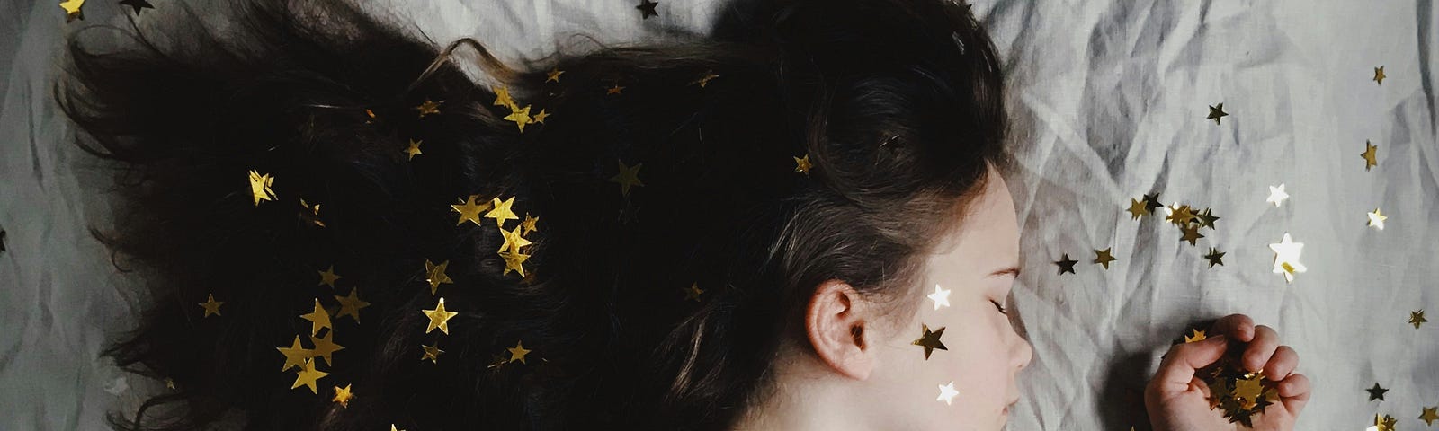 Brown-haired girl sleeping on a bed covered in stars.