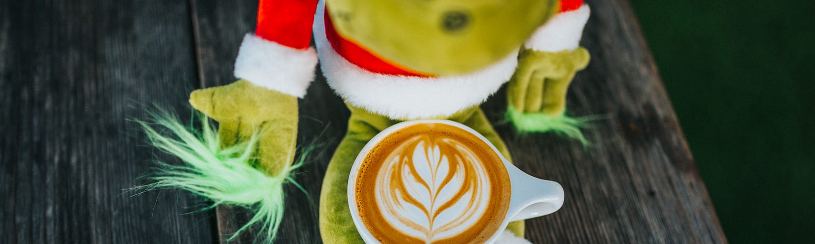 a grinch stuffed doll with a mug of coffee in it’s lap