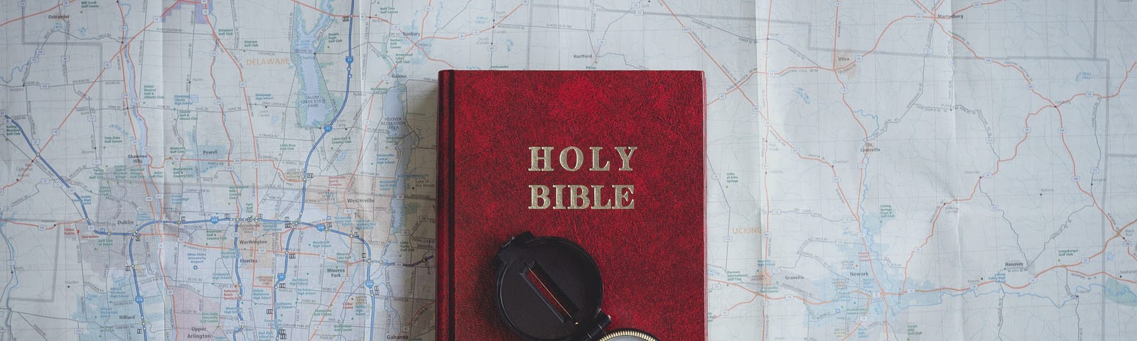 Bible with a compass on top of a map