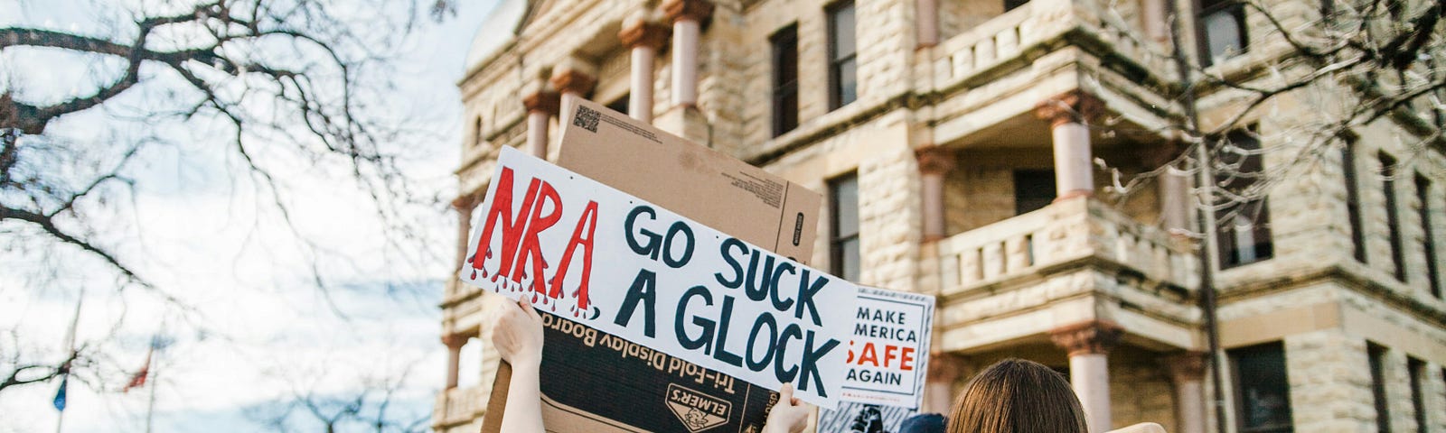 Gun protest — woman holding a sign saying NRA Go Suck A Glock