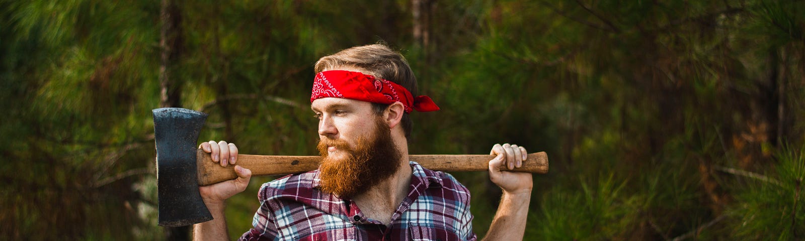 A lumberjack in a plaid shirt, with an axe over his shoulders