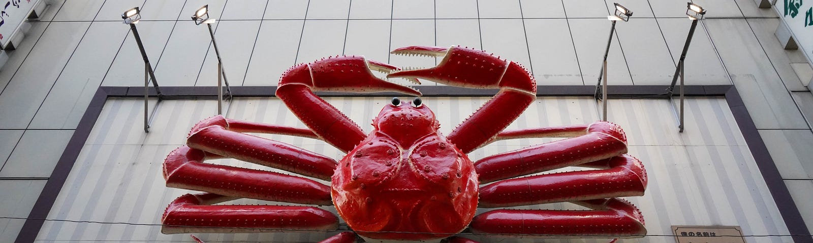 A large metal statue of a red (cooked) snow crab.
