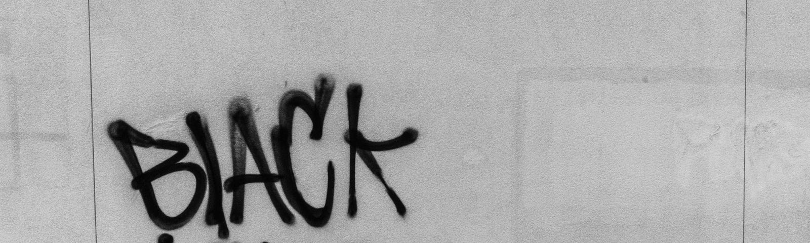 Simple black graffiti displaying the slogan: “Black Lives Matter!”