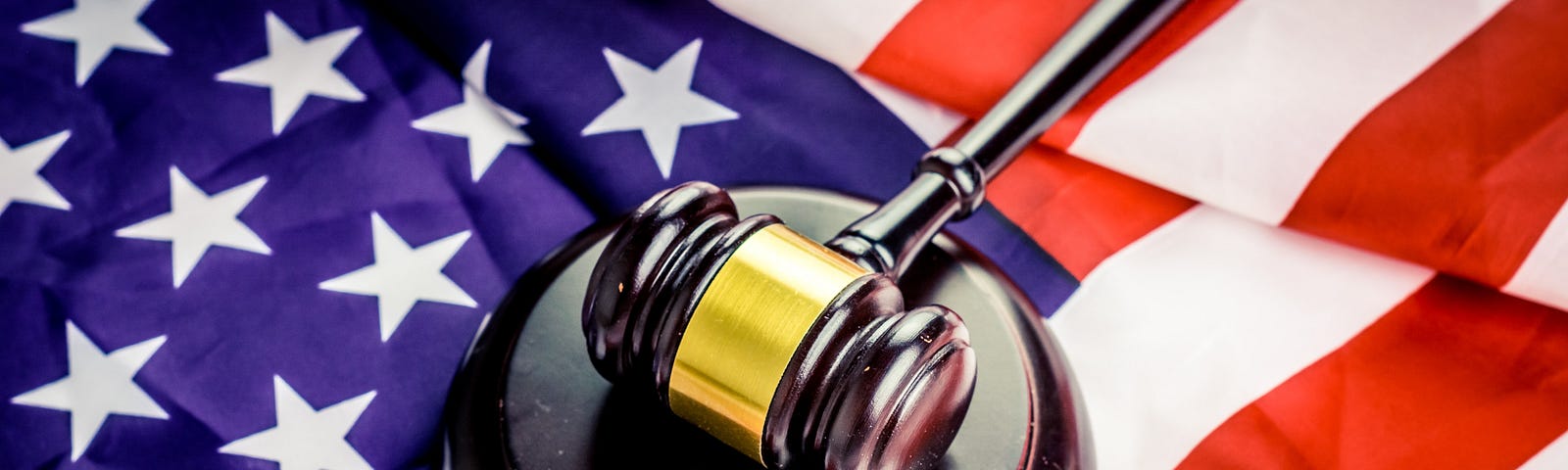 A gavel and sound block with the flag of the United States underneath.