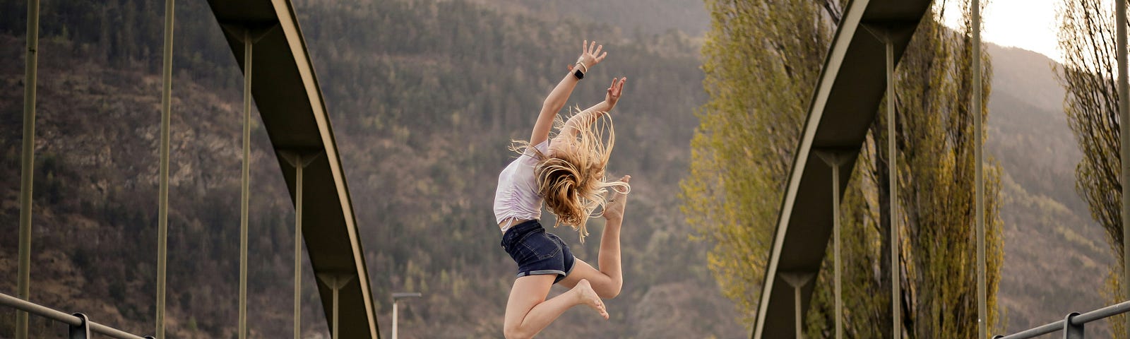 woman jumping up in the air on a bridge