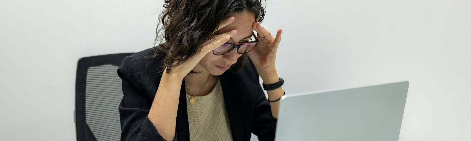Woman sitting at a desk, focused very intently on her laptop.