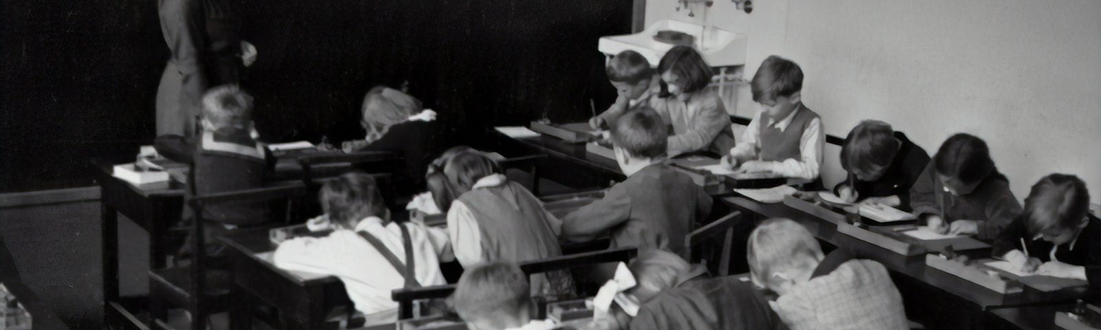 Black and white photo of children in desks at school