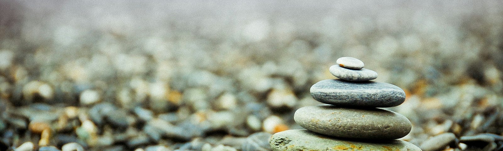 A stack of smooth stones balanced on a pebble beach, symbolizing simplicity, balance, and tranquility.