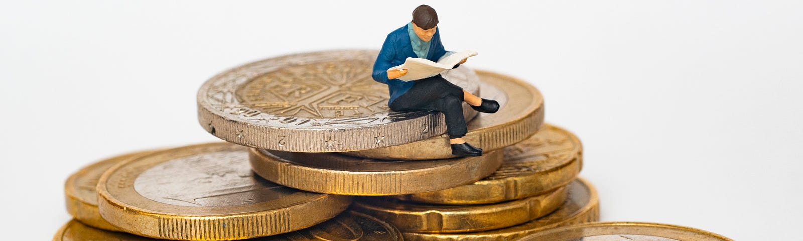 A toy of a man reading a book on a stack of coins