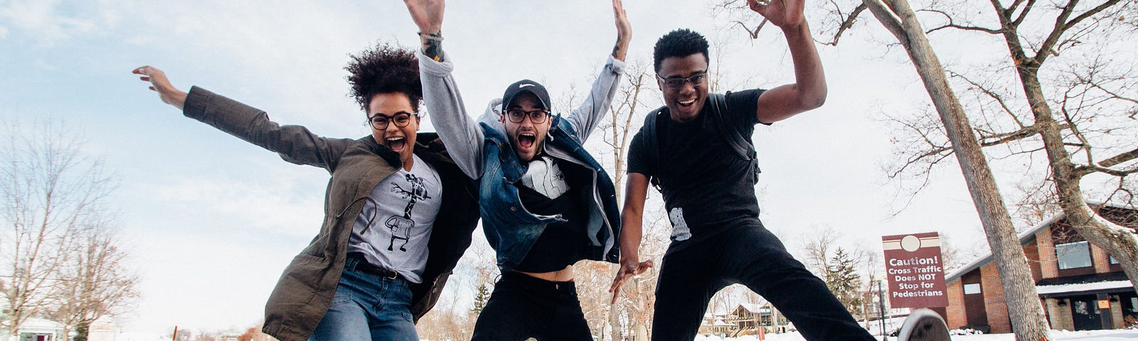 Three young adults jumping in the air and smiling.