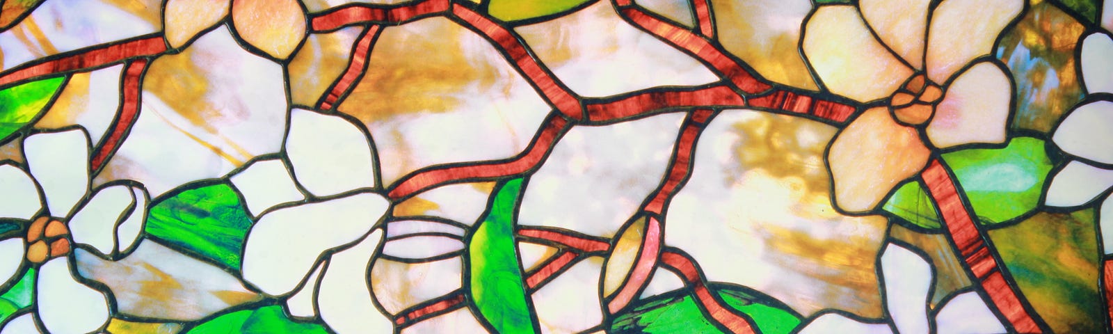 A stained-glass window of tree branches with white and cream blossoms.