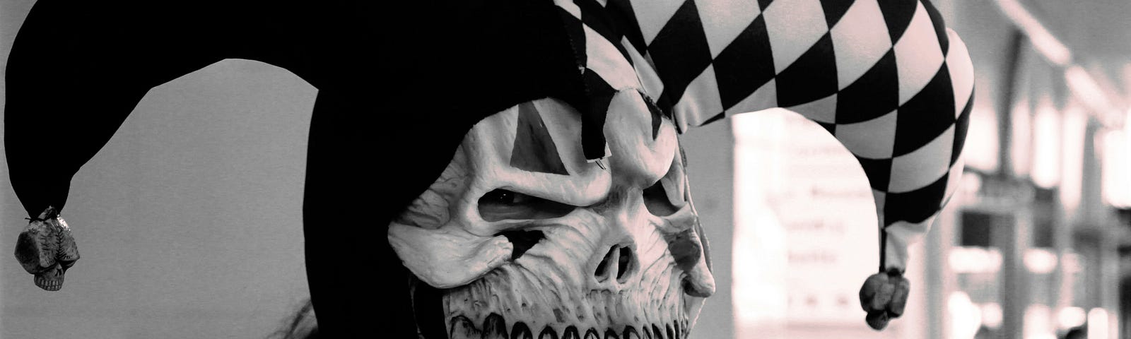 Someone in a black and white fool costume and a skull mask.