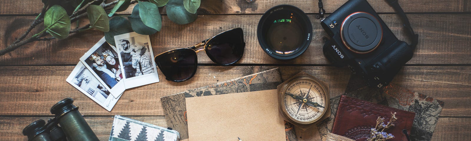 Travel items including sunglasses, camera, compass and journals