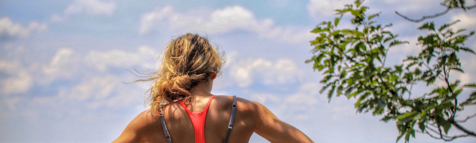 Woman wearing workout clothes taking a break after a run, staring off at a mountain view