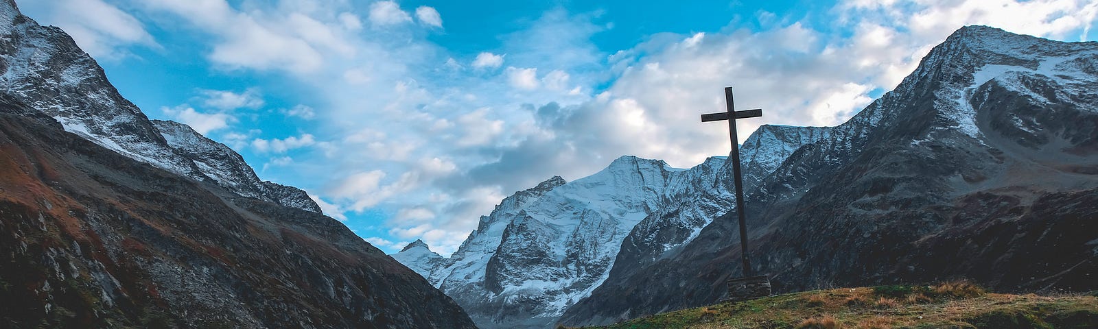 Here is a picture of rolling hills with sheep grazing. There is a cross in the distance, representing the Christian faith.