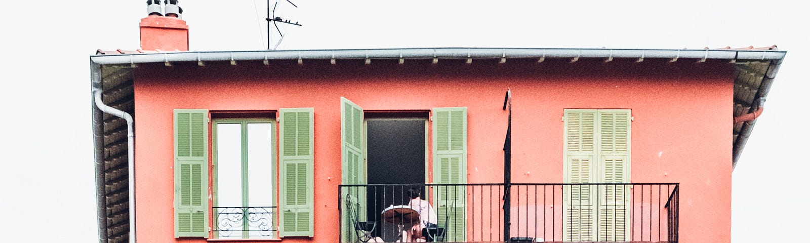 A pinkish-red apartment building with multiple porches