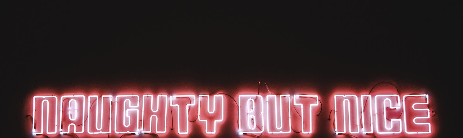 Neon sign, “Naughty But Nice” in all caps.