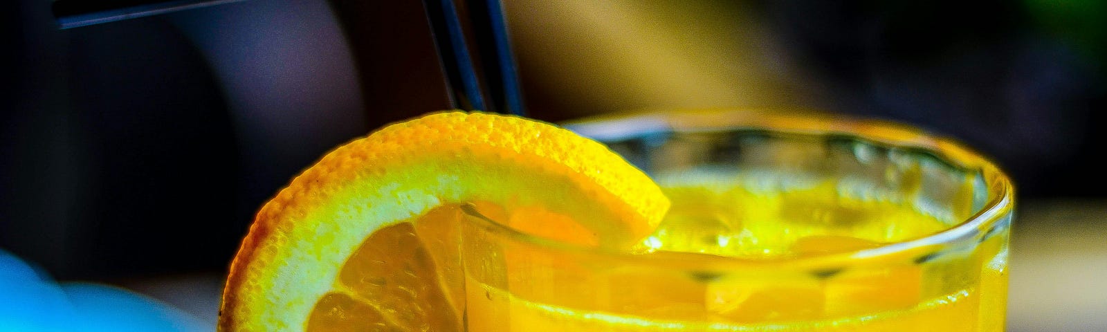 A glass of orange juice, with a slice of orange at its top.