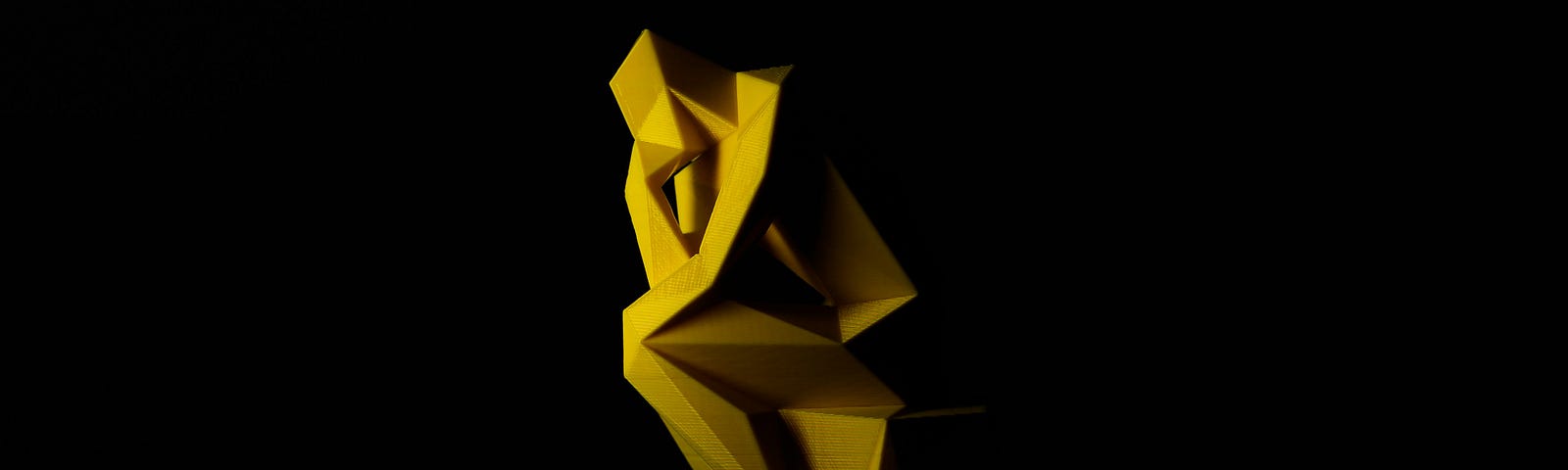 A modern yellow sculpture that evokes Auguste Rodin’s The Thinker against a black background