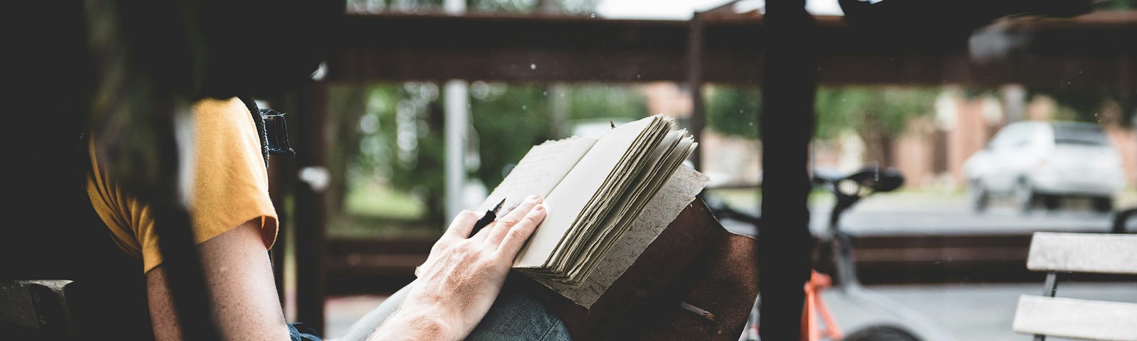 Woman writing outside on a bench.