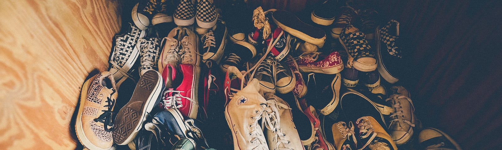 A wooden cubby filled with dozens of disordered shoes, each varying in color, shape, and position.