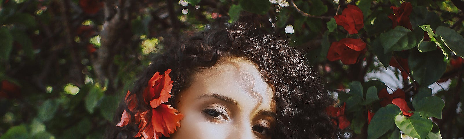 Beautiful woman of color with a red flower in her hair.